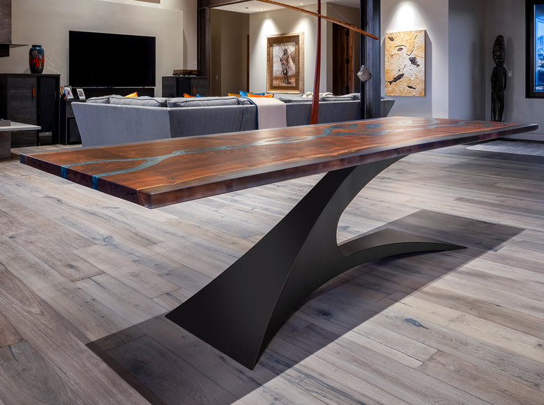 Wooden dining table with blue resin inlay and black metal base in a stylish living room.