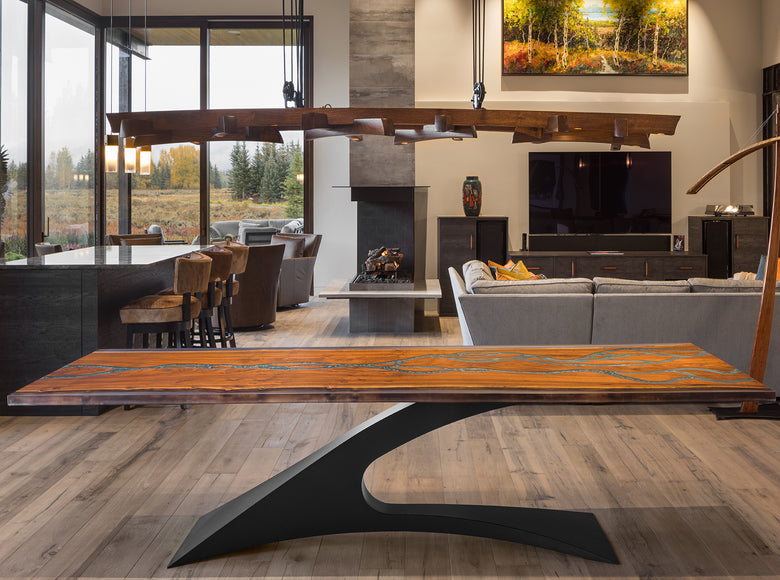Modern living room with a wooden dining table with blue resin inlay and black metal base and gray sofa.