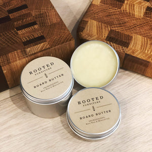 Rooted Board Butter in a tin next to two cutting boards